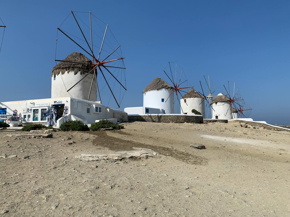 The white windmills of Mykonos standing on a hill above the town