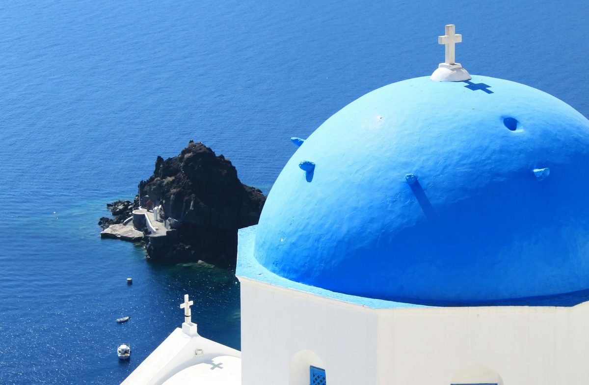 A blue domed church above the caldera sea on Santorini