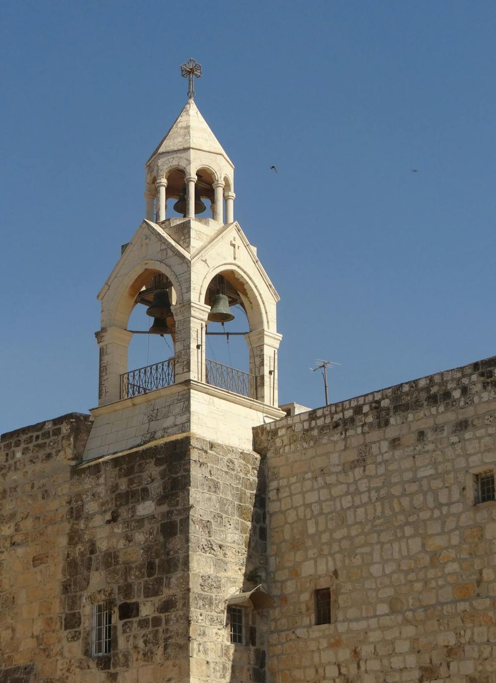 The stone bell tower of the Church of the Nativity in Bethlehem crowned with a cross