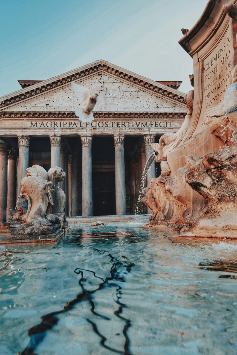 The columned portico of the Pantheon in Rome seen across the piazza fountain